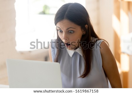 Young businesswoman seated at workplace desk make big eyes gawp look at computer screen feels shocked critical error project lost not saved information, problems with device, unbelievable news concept