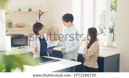 Young businesswoman showing house interior for asian couple.