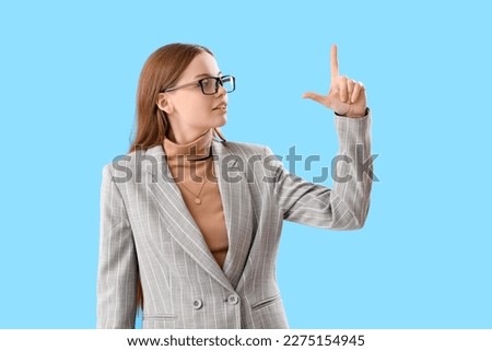 Young businesswoman showing loser gesture on blue background