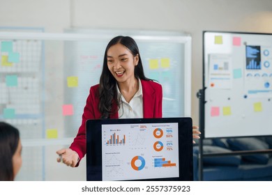 Young businesswoman showing positive financial charts and statistics on a digital tablet during a presentation in a modern office - Powered by Shutterstock