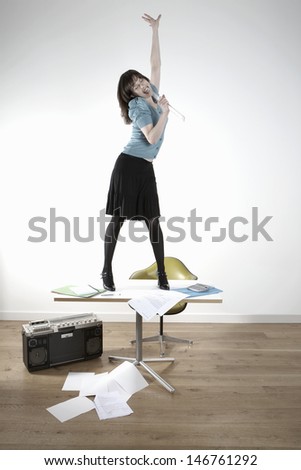 Young businesswoman singing on desk while listening to tape recorder