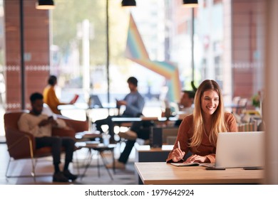 Young Businesswoman Sitting At Desk Writing In Notebook In Modern Open Plan Office - Shutterstock ID 1979642924