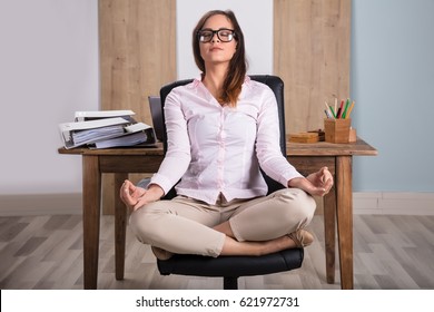 Young Businesswoman Sitting On Chair Meditating In Office