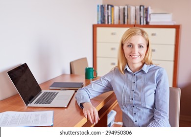 A young businesswoman smiling at the camera while sitting in her office