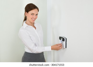 Young Businesswoman Smiling While Inserting Keycard In Door Security System