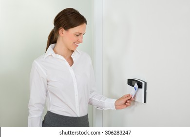 Young Businesswoman Smiling While Inserting Keycard In Door Security System