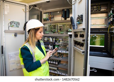 Young businesswoman standing in front of the control panel in the control room - Powered by Shutterstock