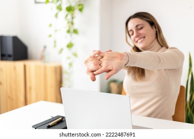 Young businesswoman stretching while working on laptop computer sitting at desk in home office - Shutterstock ID 2222487691