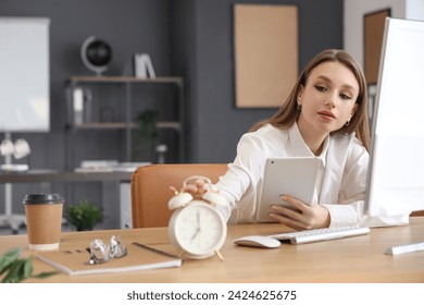 Young businesswoman with tablet computer and alarm clock on table in office. Time management concept - Powered by Shutterstock