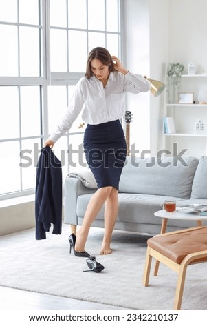 Young businesswoman taking her shoes off at home after long working day