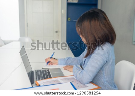 Young businesswoman taking notes in notebook and sitting in the businessroom