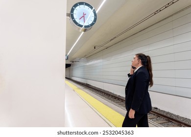 Young Businesswoman Talking on Phone While Checking Time at Train Station Platform - Powered by Shutterstock