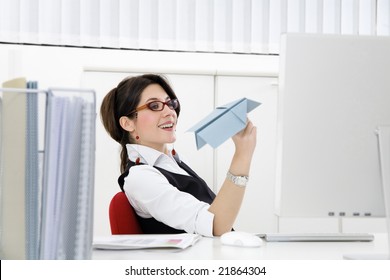 Young Businesswoman Throwing Paper Airplane In Office