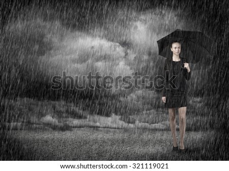 Young businesswoman with umbrella standing in rain
