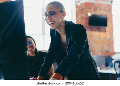 Young businesswoman using a desktop while working with her colleagues. Happy young businesswoman smiling cheerfully while standing next to her colleague at an office desk. Colleagues working together. - Shutterstock ID 2094180652