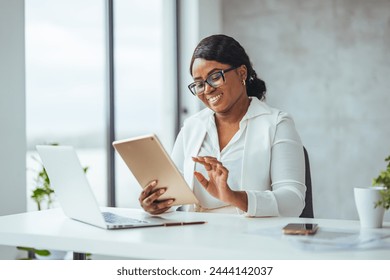 Young businesswoman using a digital tablet and laptop in a modern office. Shot of a young businesswoman using a digital tablet while at work. The better connected, the easier the workflow - Powered by Shutterstock