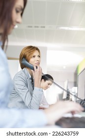 Young Businesswoman Using Landline Phone In Office