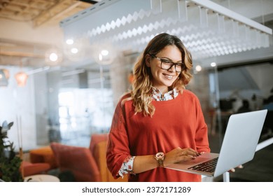 Young businesswoman using a laptop at a modern office - Powered by Shutterstock