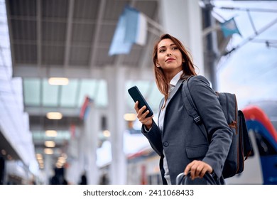 Young businesswoman using smart phone while arriving at train station. Copy space.