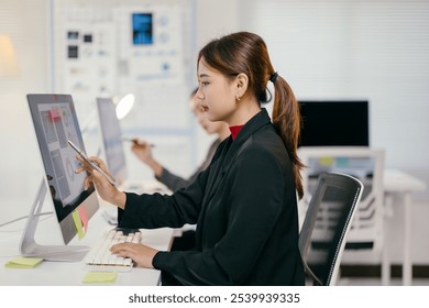 Young businesswoman is using a stylus to interact with a computer screen displaying charts and graphs, suggesting data analysis and decision-making in a professional setting - Powered by Shutterstock