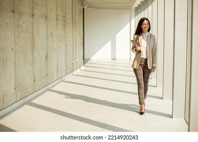 Young Businesswoman Walking On Modern Office Hallway On A Sunny Day