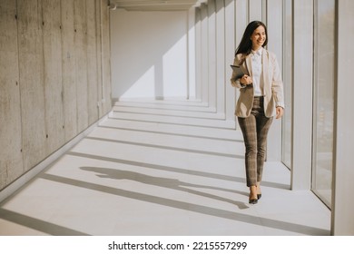 Young Businesswoman Walking On Modern Office Hallway On A Sunny Day