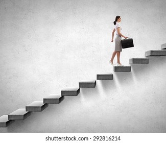 Young businesswoman walking up on staircase representing success concept