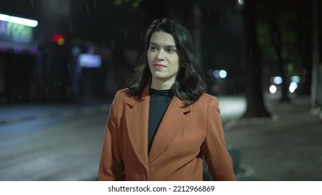 Young businesswoman walking in street at night during rain drizzle. Carefree millennial adult girl walks alone in city downtown - Powered by Shutterstock