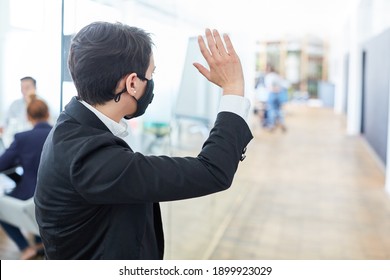 Young Businesswoman Waves To Colleagues As A Greeting In Open Plan Office