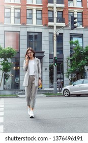 Young Businesswoman Wearing Eyeglasses Walking From The Building On The City Street Talking On Smartphone Smiling Cheerful Full Body Shot