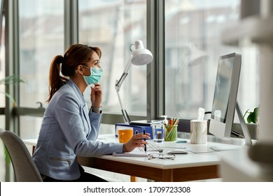 Young businesswoman wearing face mask while working on a computer in the office.  - Powered by Shutterstock