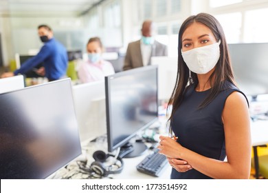 Young businesswoman wearing face mask as protection against Covid-19 and corona virus in open plan office - Powered by Shutterstock