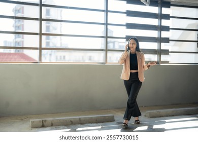 Young businesswoman wearing smart casual attire is making a phone call while walking in a parking garage, gesturing with her hand as she speaks - Powered by Shutterstock