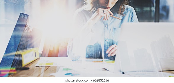 Young businesswoman working process at modern office.Account manager working at the wooden table with paper documents.Double exposure,skyscraper building blurred background.Wide,flares effect - Shutterstock ID 662831656