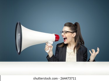 Young businesswoman yelling over megaphone
