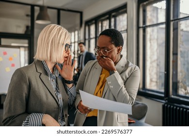 Young businesswomen checking paperwork. Focused designers standing in their agency. Creative entrepreneurs working and gossiping. - Powered by Shutterstock