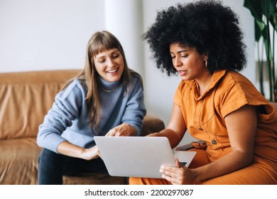 Young businesswomen having a discussion while using a laptop together. Two female entrepreneurs working as a team in a modern workplace. - Powered by Shutterstock