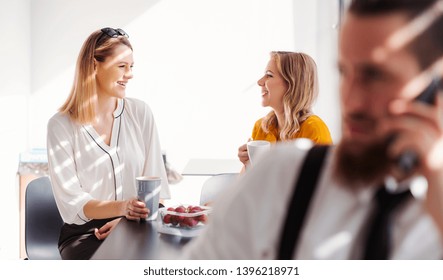 Young Businesswomen On Coffee Break In Office Kitchen, Talking.