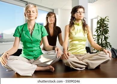 Young businesswomen sitting in yoga position on meeting room table. - Powered by Shutterstock