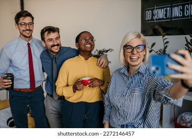 Young businesswomen taking self portrait picture of herself with male office colleagues using smartphone in modern office - Powered by Shutterstock