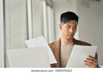 Young busy Asian business man lawyer, tax accountant manager holding paper documents checking bills, doing sales invoice accounting data, reading legal contract or bank statement in office. - Powered by Shutterstock