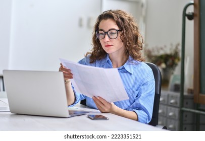 Young busy business woman manager, lawyer or company employee holding accounting bookkeeping documents checking financial data or marketing report working in office with laptop. Paperwork management - Shutterstock ID 2223351521