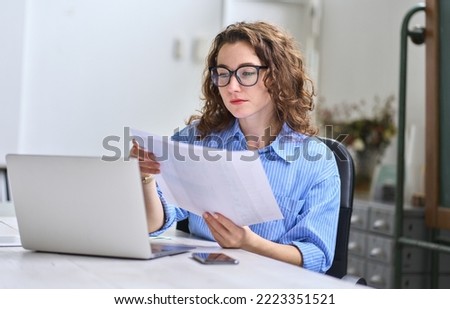 Young busy business woman manager, lawyer or company employee holding accounting bookkeeping documents checking financial data or marketing report working in office with laptop. Paperwork management Сток-фото © 