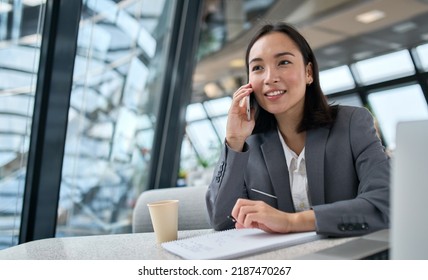 Young Busy Chinese Business Woman Talking On Phone Working In Modern Office. Asian Businesswoman Company Sales Client Manager Wearing Suit Making Call On Cellphone Sitting At Workplace.