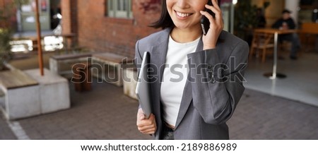 Young busy elegant business woman client manager, retail sales professional, businesswoman executive wearing suit talking on the phone making mobile business call standing outdoors, close up.