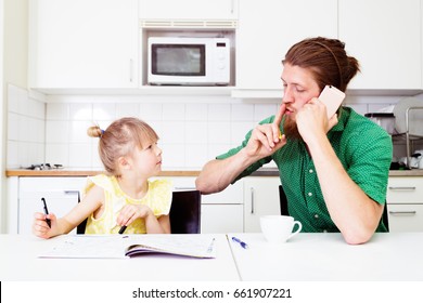 Young Busy Father Helping Daughter Preschooler With Homework, Talking By Phone At Home On Kitchen. Occupied Parent Have No Time For Kid At Home. Dad Working While Kid Studying.