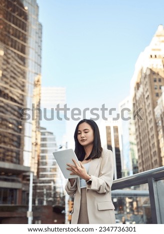 Young busy pretty Asian business woman professional office manager executive or global international company employee standing on big city street outside using digital tablet fintech device, vertical.