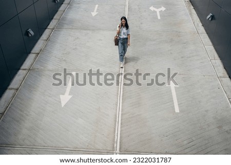 Young busy successful beautiful Japanese business woman, Japanese professional businesswoman holding cellphone using smartphone standing or walking on big city urban street outside