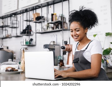 Young Cafe Owner Working On Her Laptop, Standing At Counter