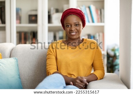 Young calm black woman wearing casual outfit relaxing on comfortable sofa in modern living room, lazy happy african american woman resting on couch, enjoy peace of mind no stress at home, copy space